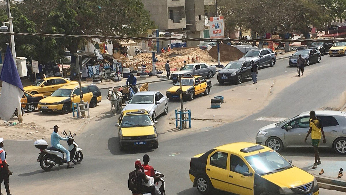 Carrefour animé à Dakar, avec des taxis jaunes et des motos